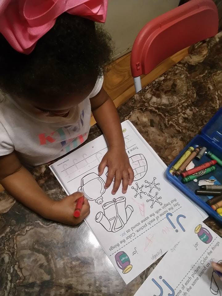 Child coloring a picture with a red crayon