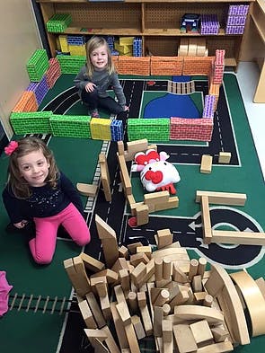 Two children playing with blocks on a rug with a road map rug
