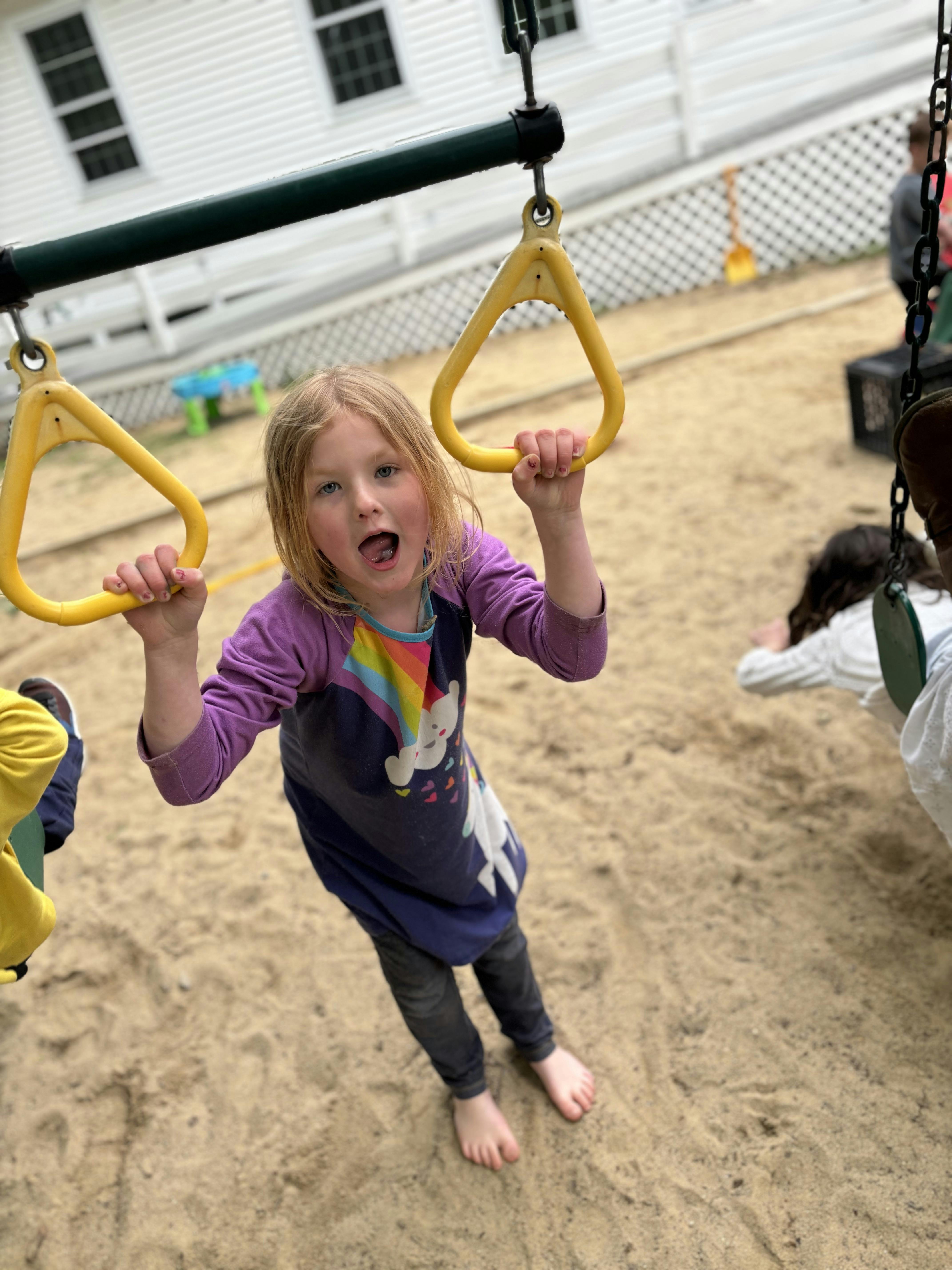 Child holding onto yellow rings on a playground