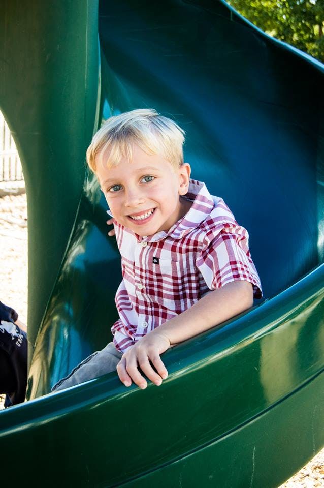 Child in a plaid shirt on a green slide