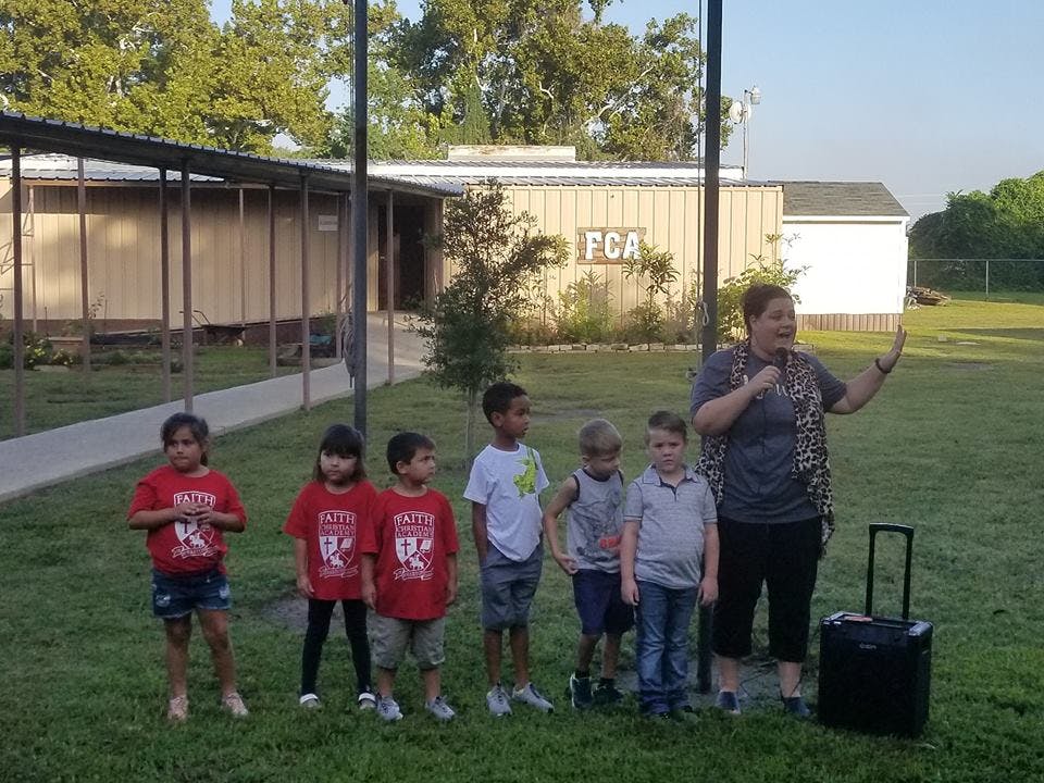 Adult speaking to a group of children outdoors