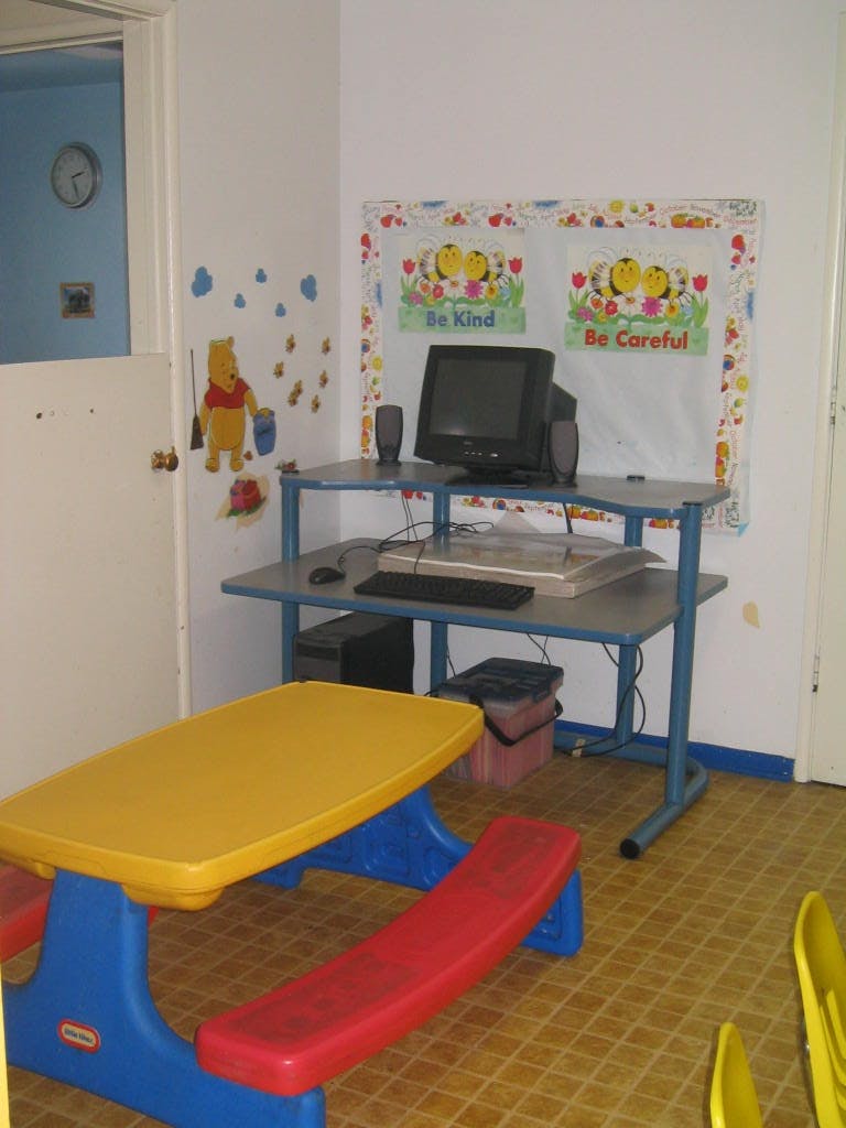 Computer desk with monitor and keyboard next to a child's picnic table