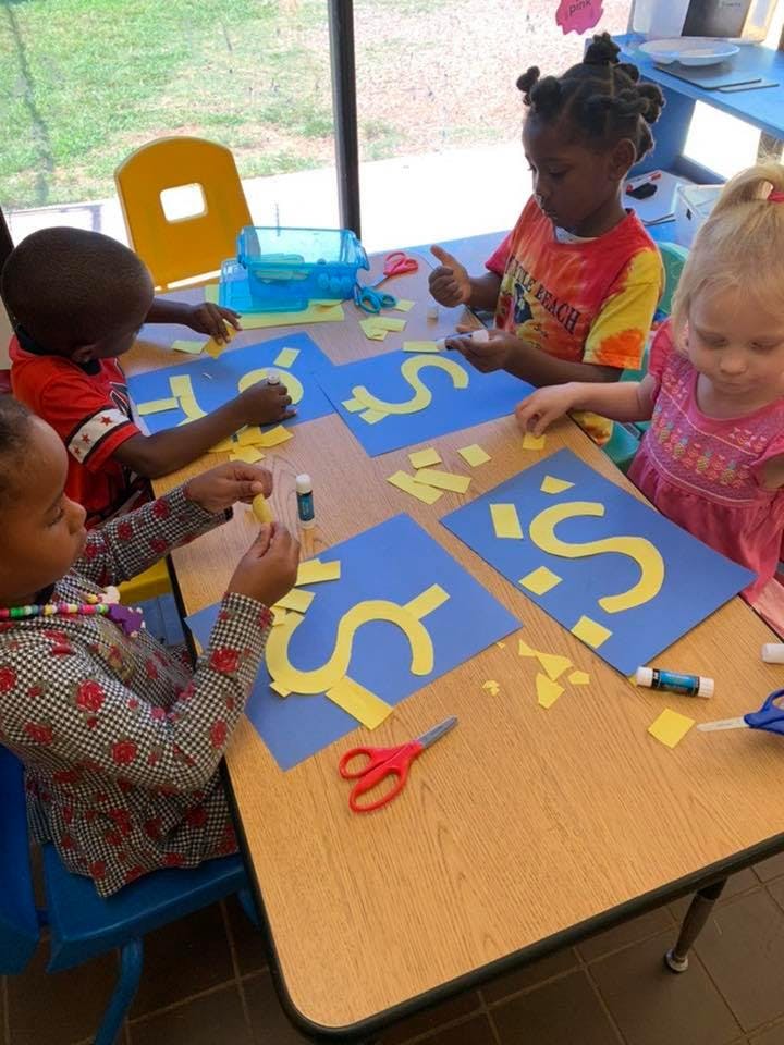 Children at a table doing crafts with paper and glue