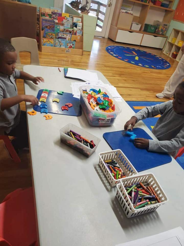 Two children playing with toys at a table in a classroom