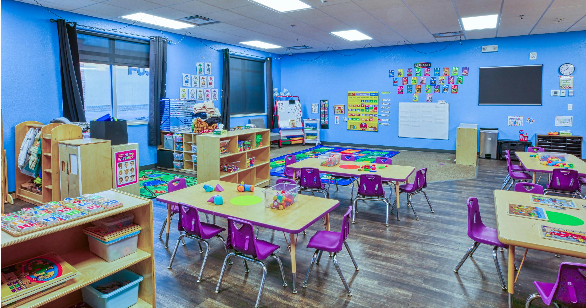 Classroom with small tables and chairs, learning posters on blue walls