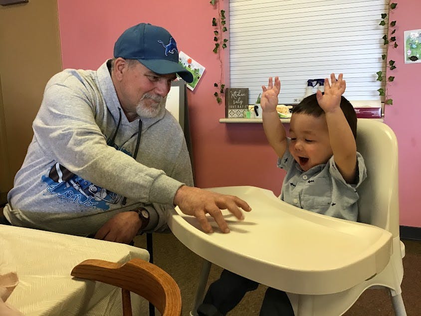 Person interacting with a child in a high chair
