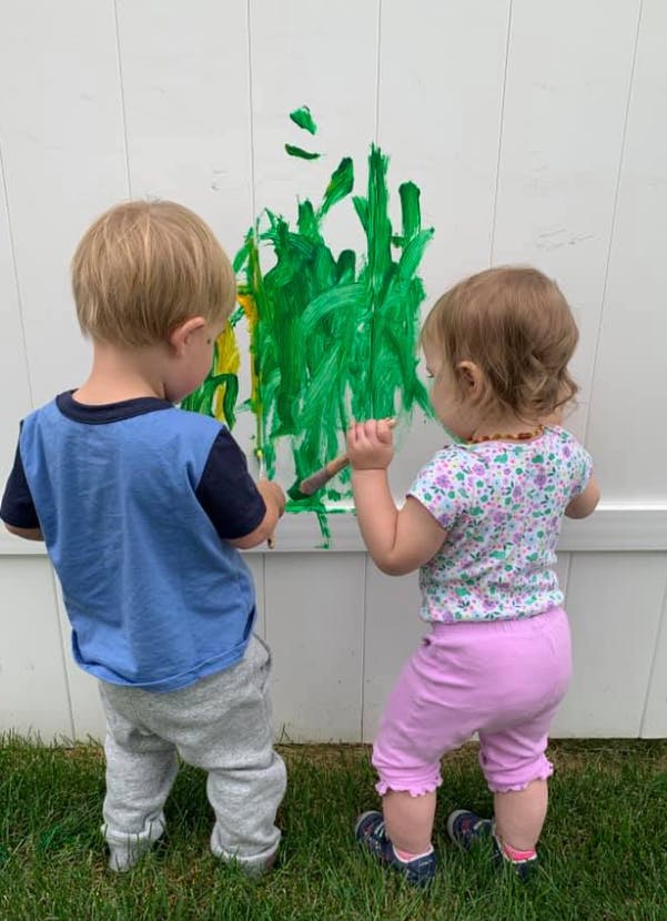Two children painting on a white wall