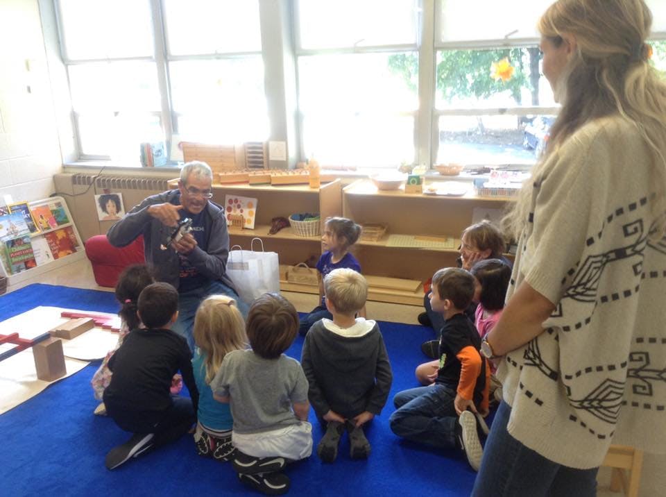 Person speaking to a group of children in a classroom
