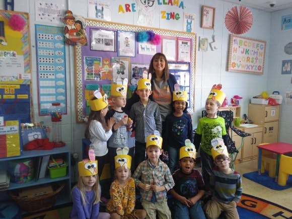 Adult and children wearing paper crowns in a classroom