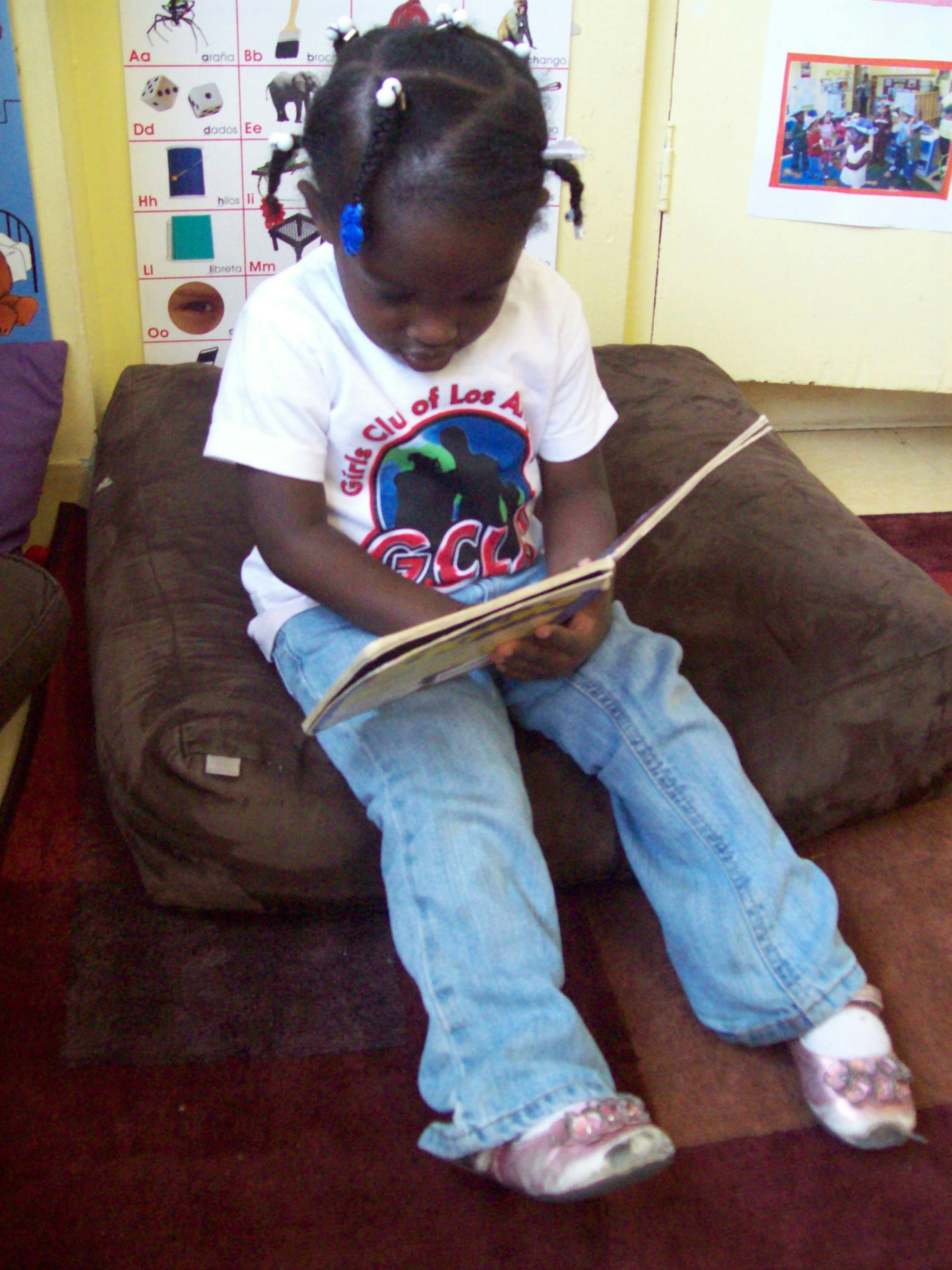 Child sitting on a cushion reading a book