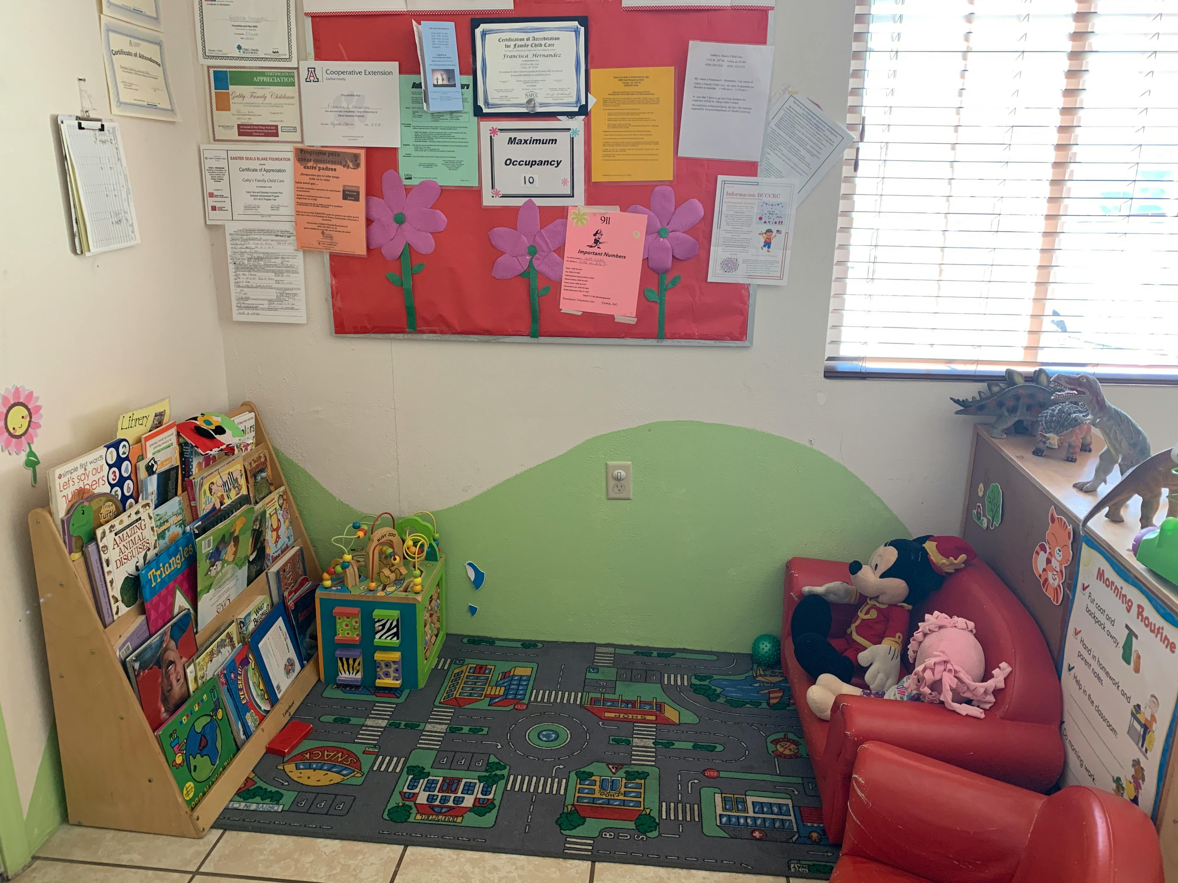 Children's reading corner with a bookshelf, rug, and small red couch