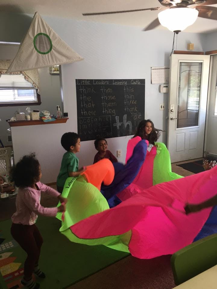 Children playing with a colorful parachute indoors