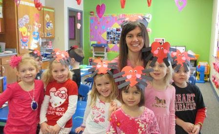 Adult and children wearing heart-themed headbands in a classroom
