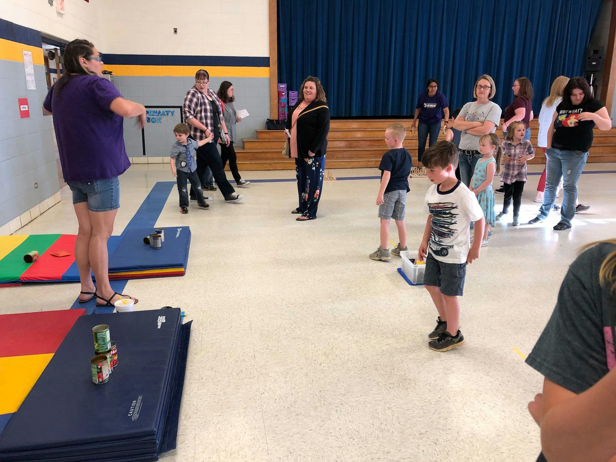 People and children in a room with blue mats on the floor