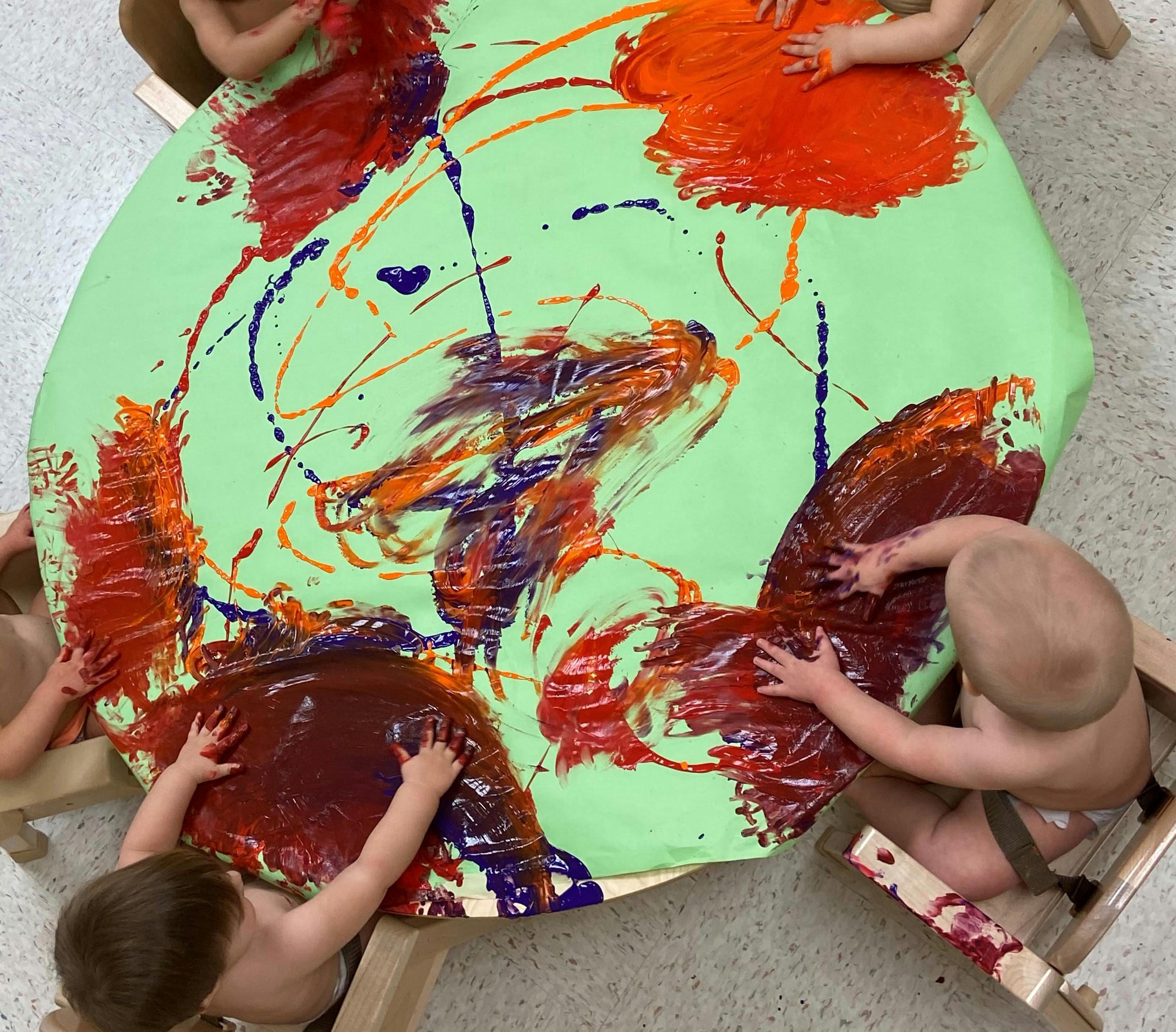 Children finger painting on a large green surface