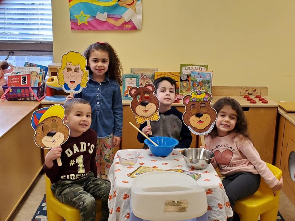 Four children holding up character masks around a table with bowls