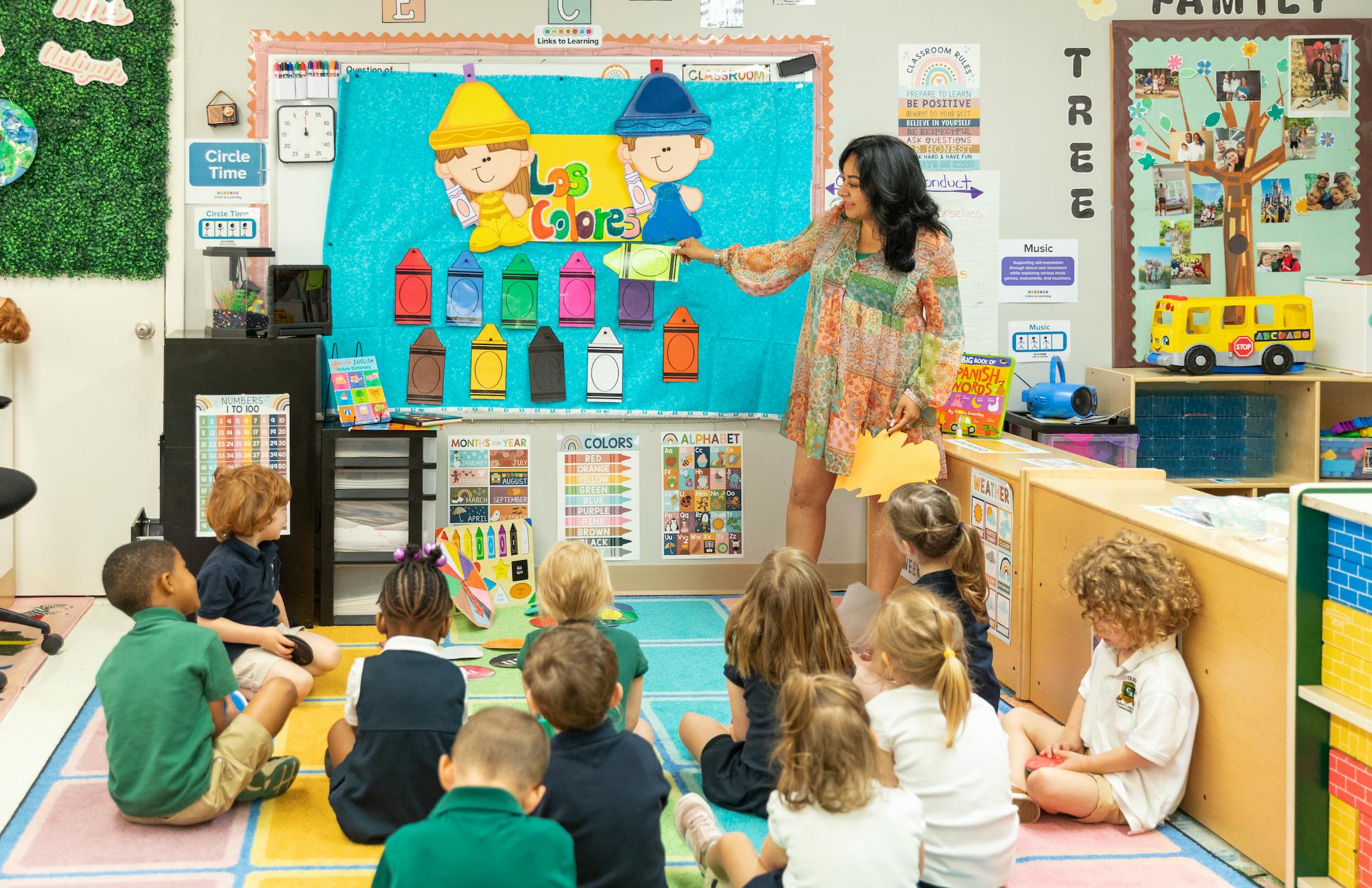 adult pointing to a colorful display in front of children sitting on the floor