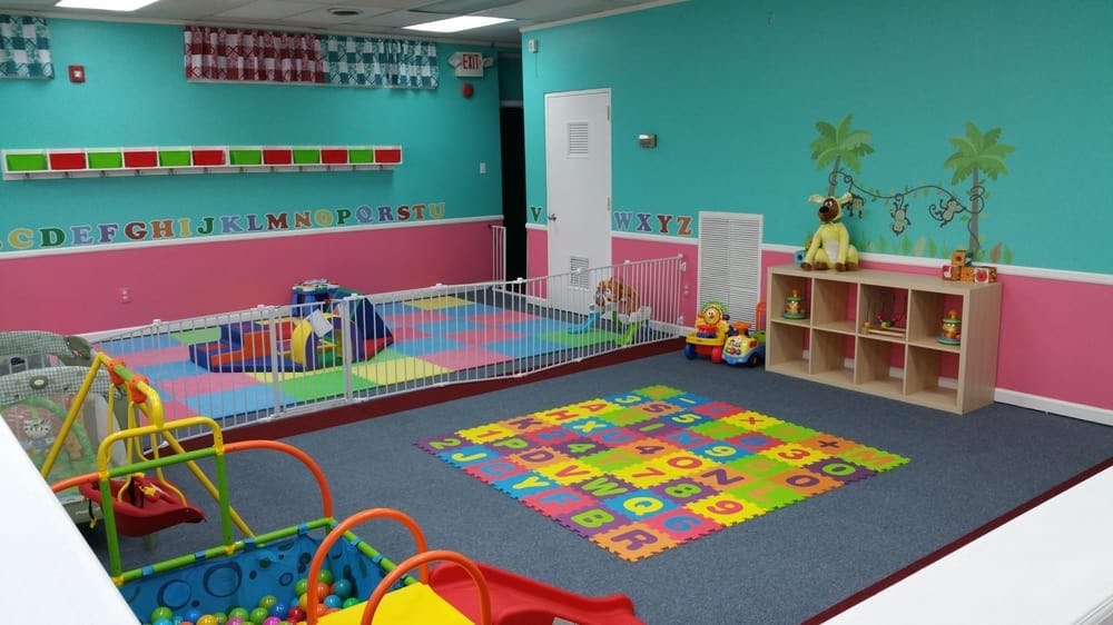 Playroom with colorful floor mats, playpen, and shelves