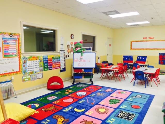 Empty classroom with colorful rug, small tables, and chairs