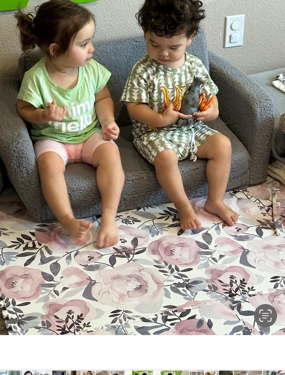 Two children sitting on a small sofa, one holding a toy