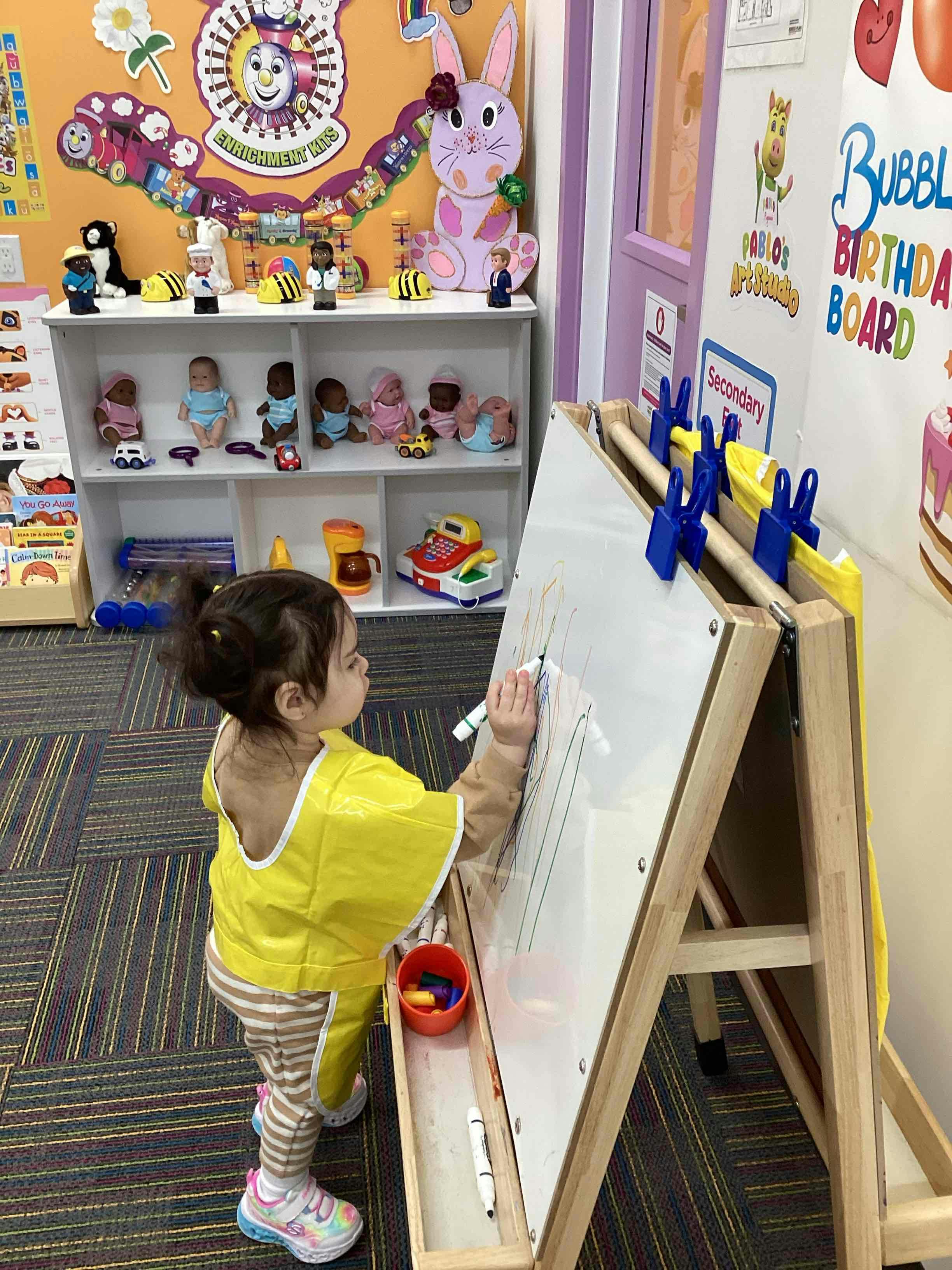 Child drawing on an easel in a classroom