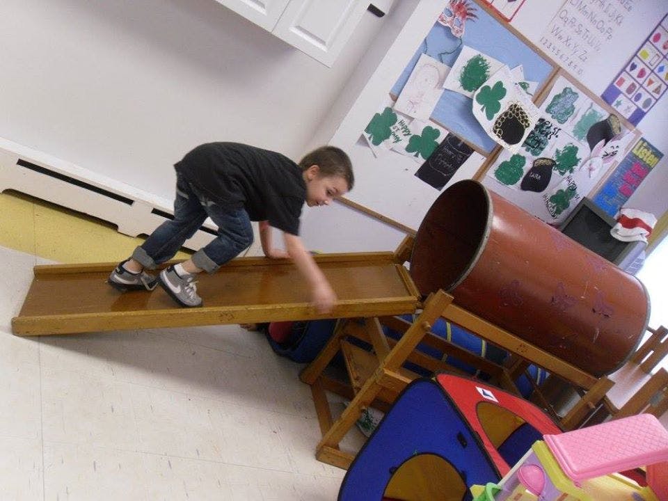 Child crawling on a wooden ramp leading to a play tunnel