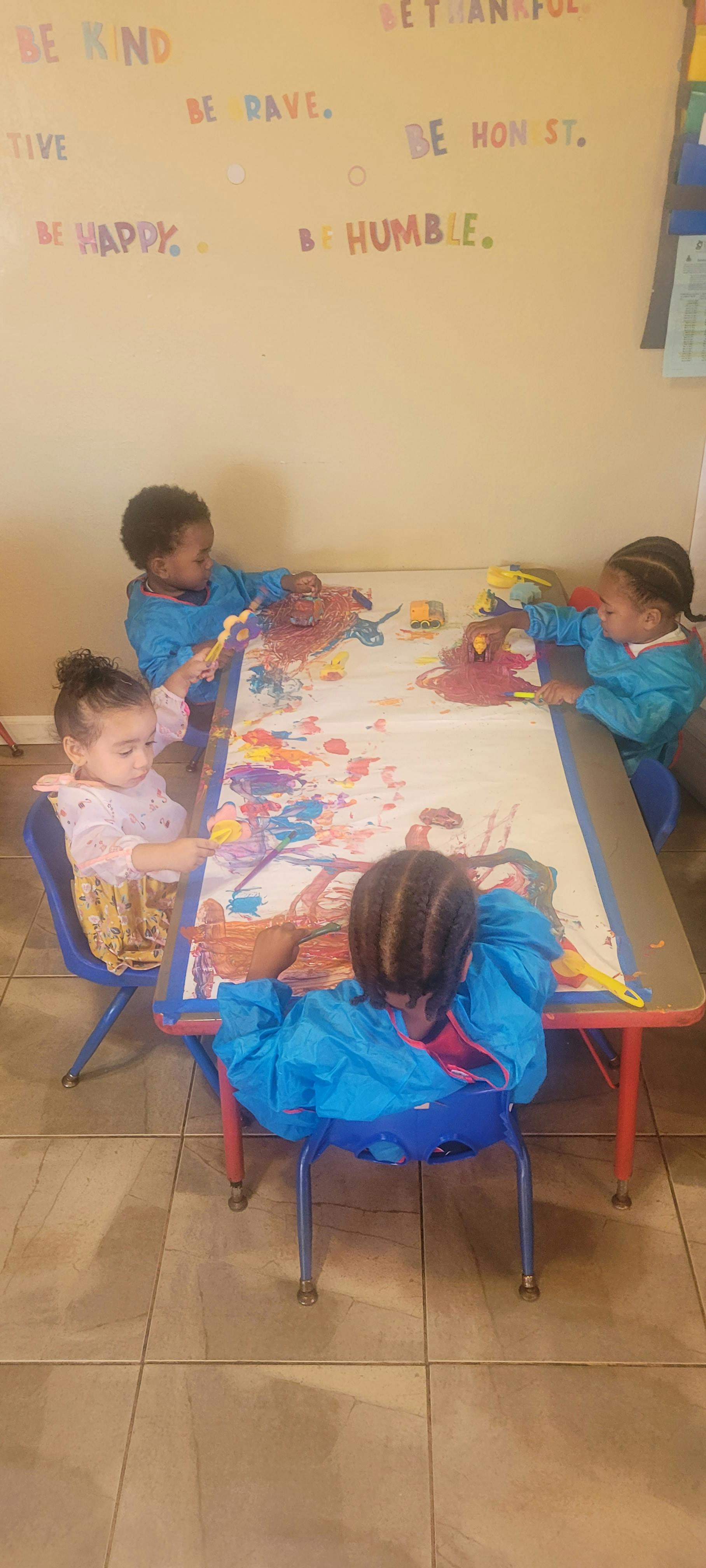 Children painting at a table in a classroom