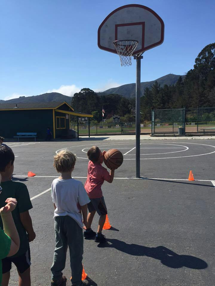 Child holding a basketball on a court with other children