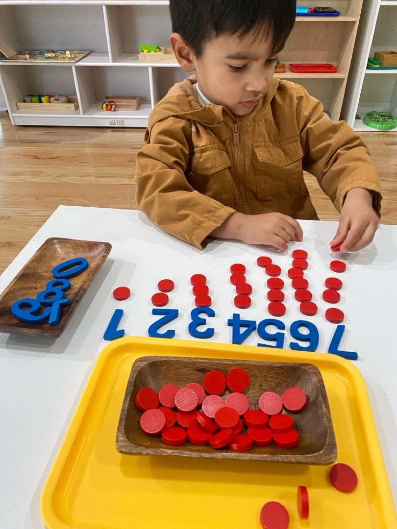 Child playing with red counters and blue number cutouts