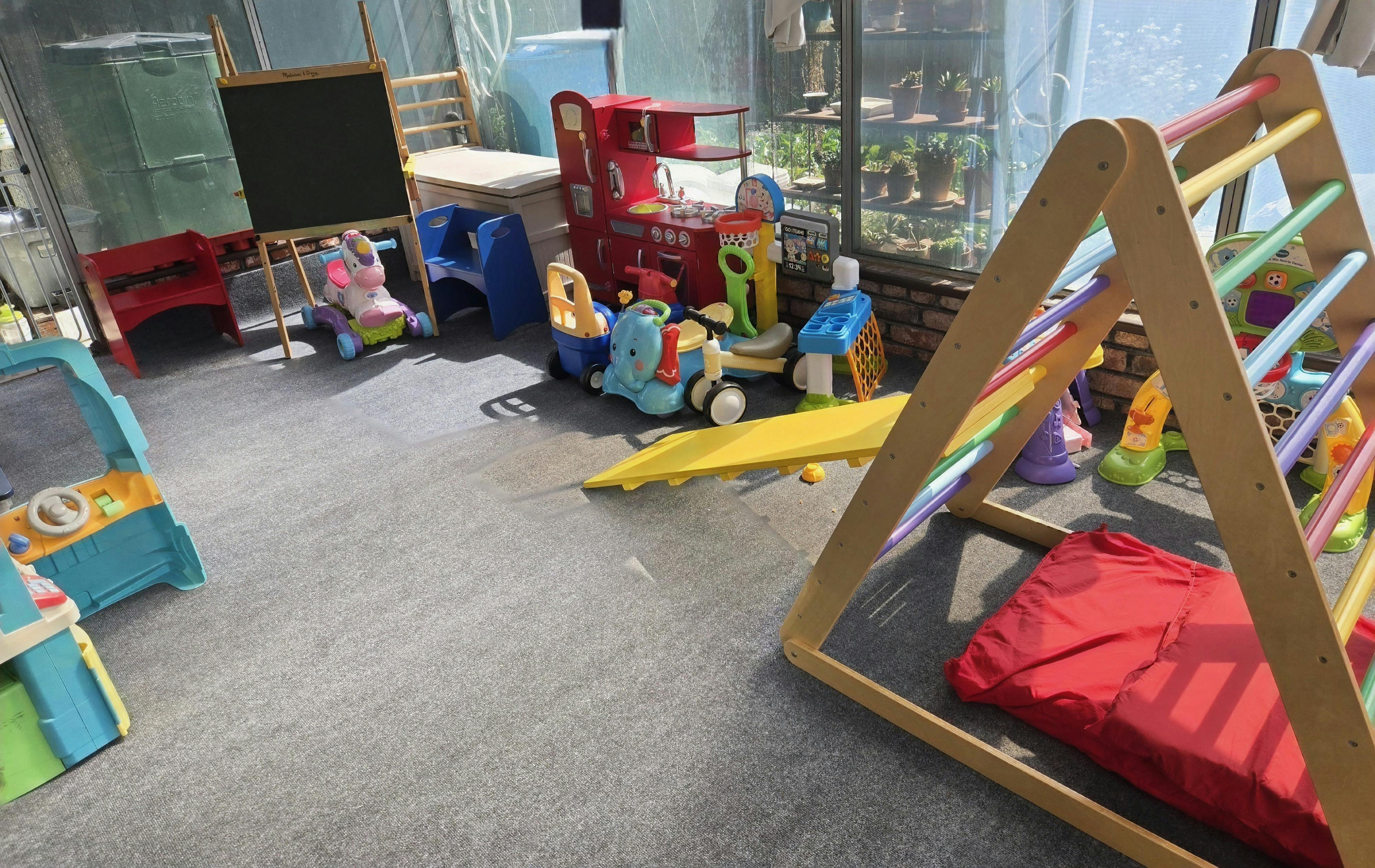 Playroom with a chalkboard, toy kitchen, ride-on toys, and climbing frame