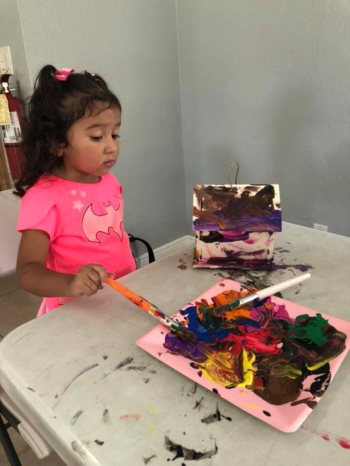 Child painting with a brush and colorful paints