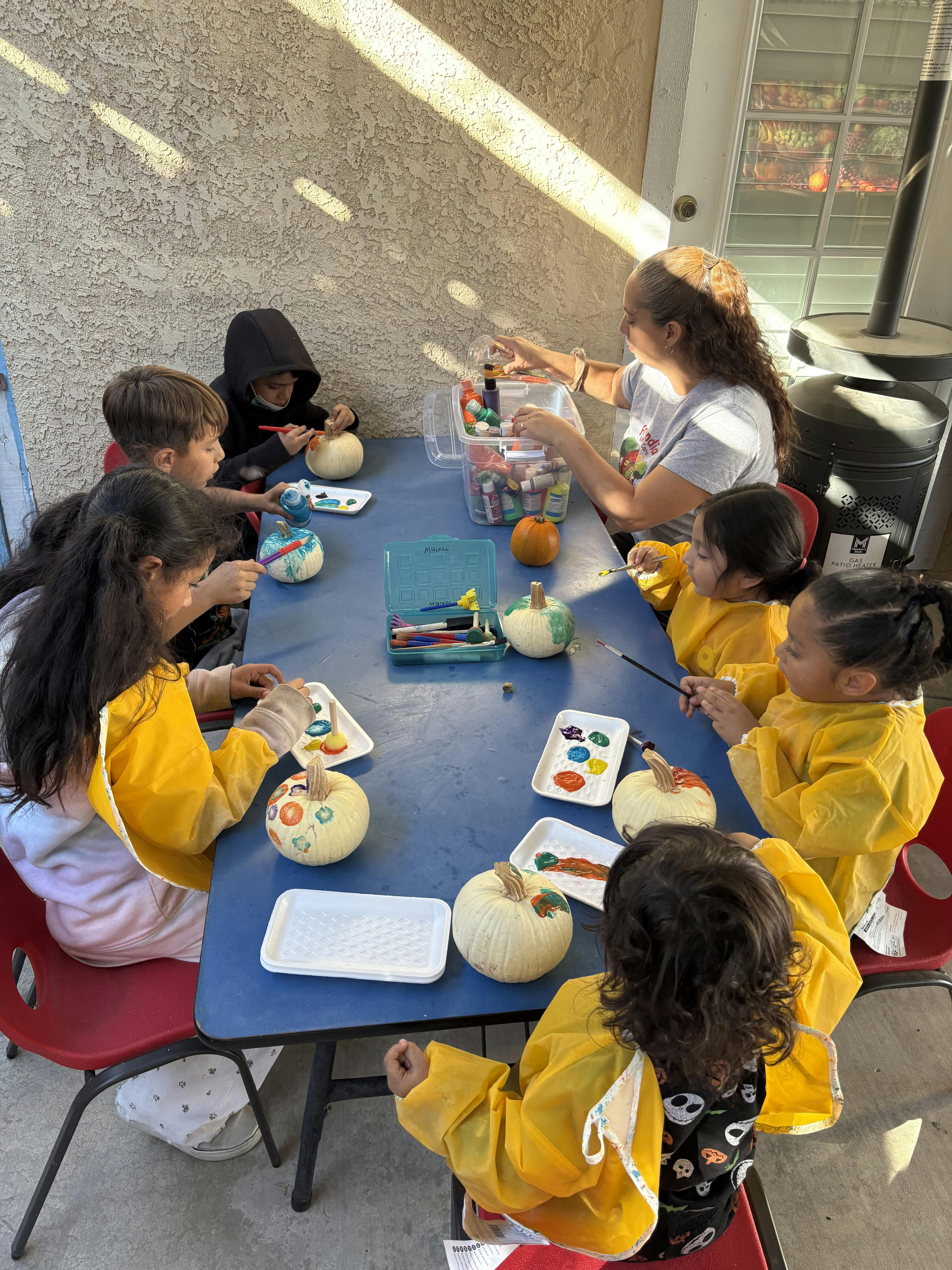 People painting pumpkins at a blue table