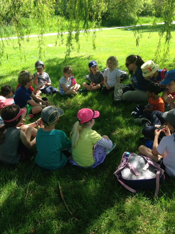 Group of children and adults sitting in a circle on grass
