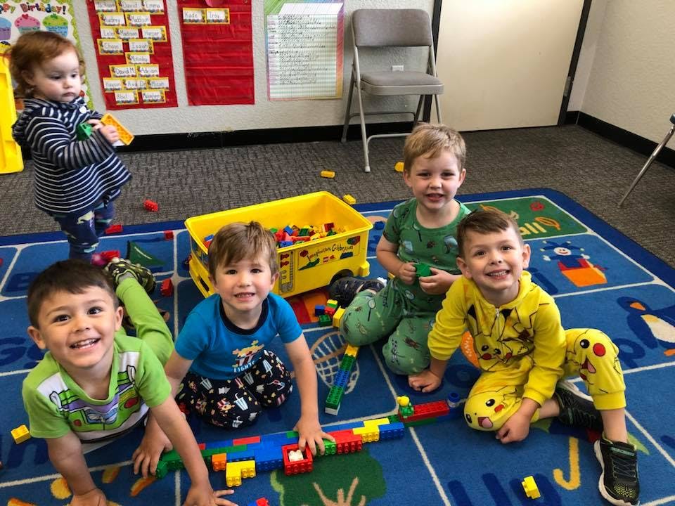 Five children playing with building blocks on a rug