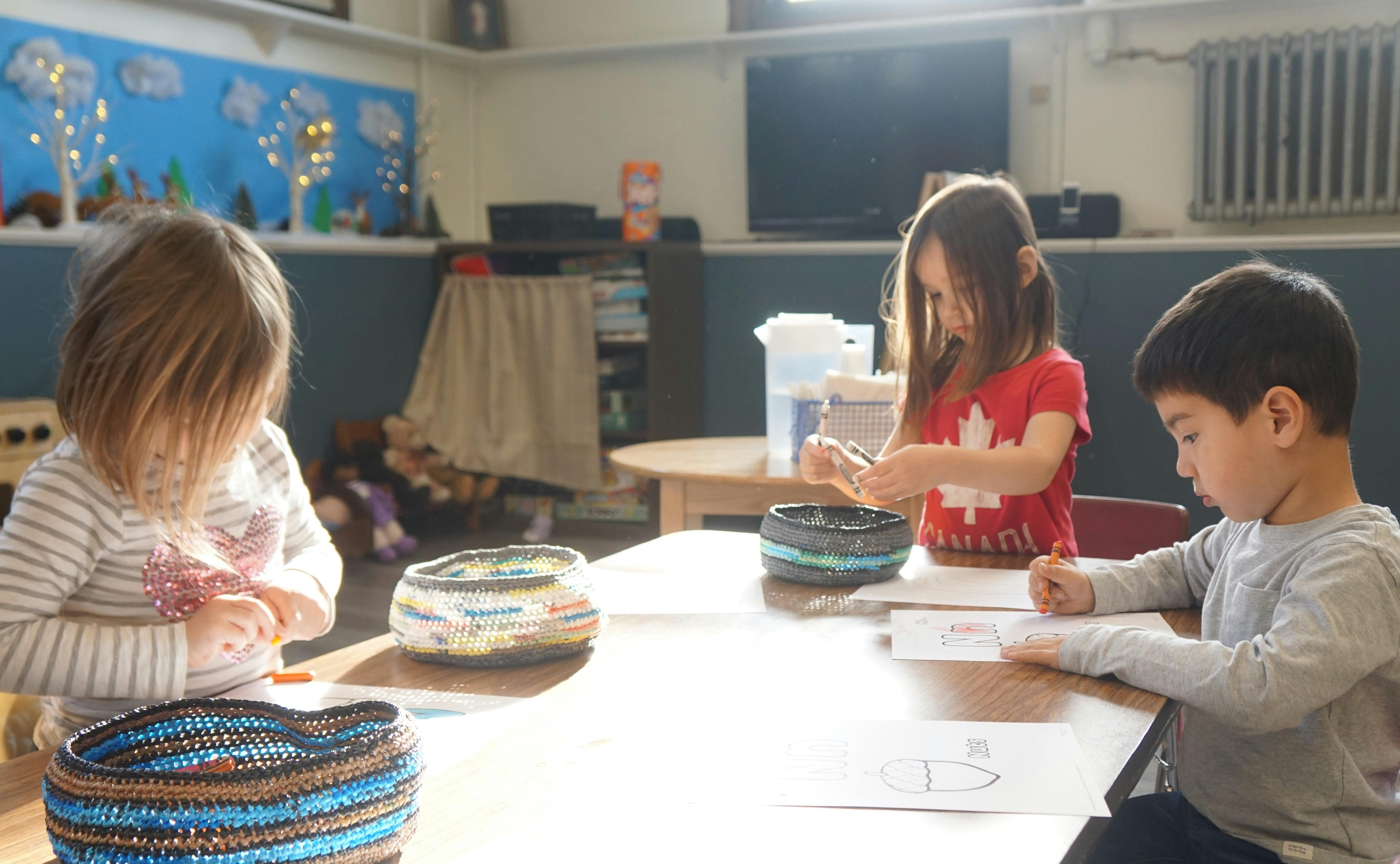 Three children at a table in a classroom