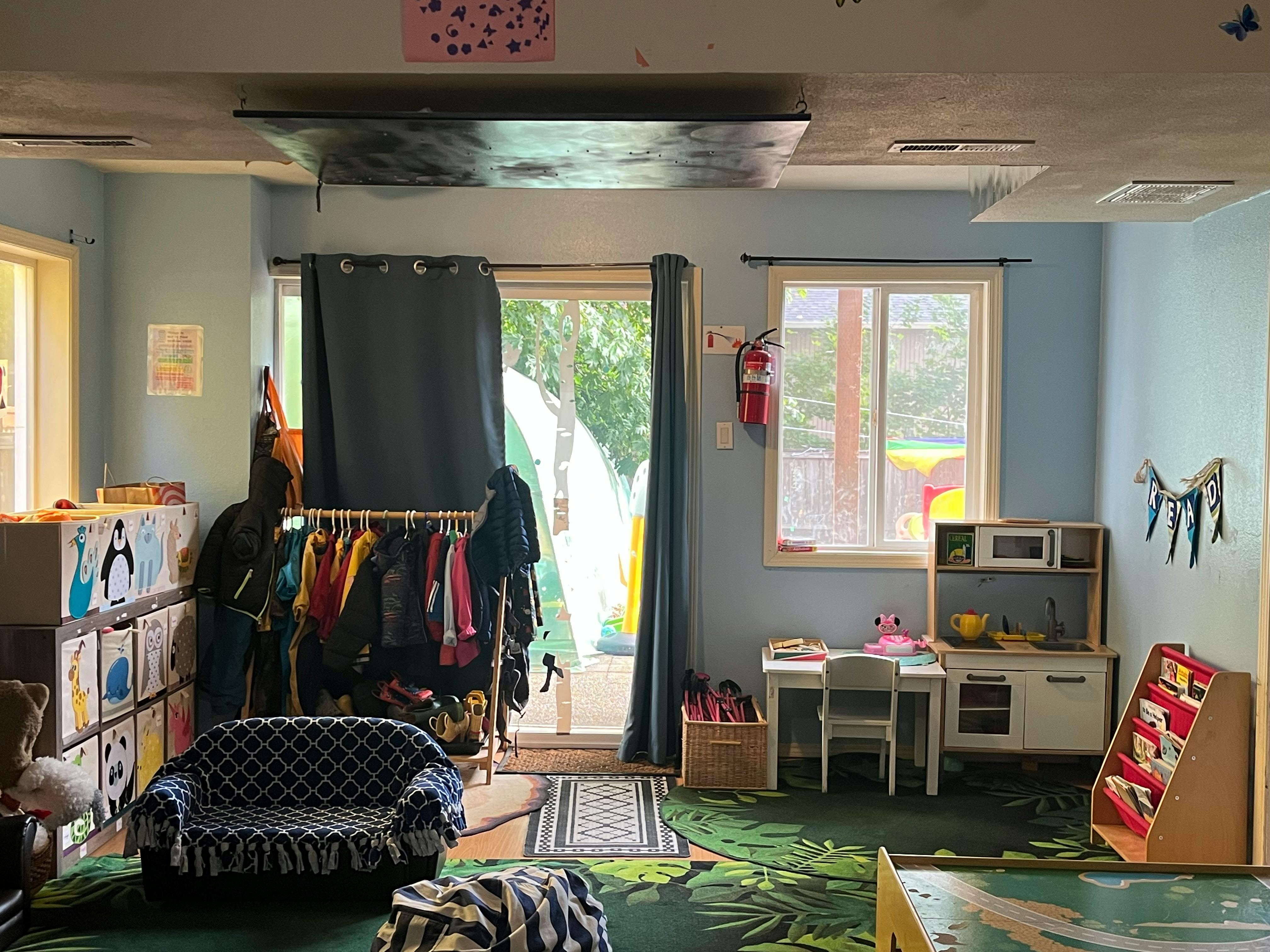 Playroom with toy kitchen, small table and chairs, and clothing rack