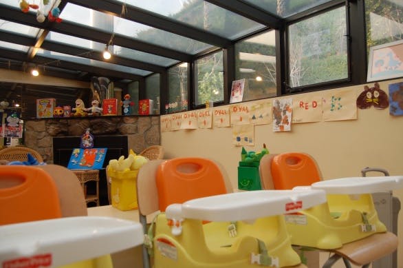 Child-sized chairs with trays in a room with large windows