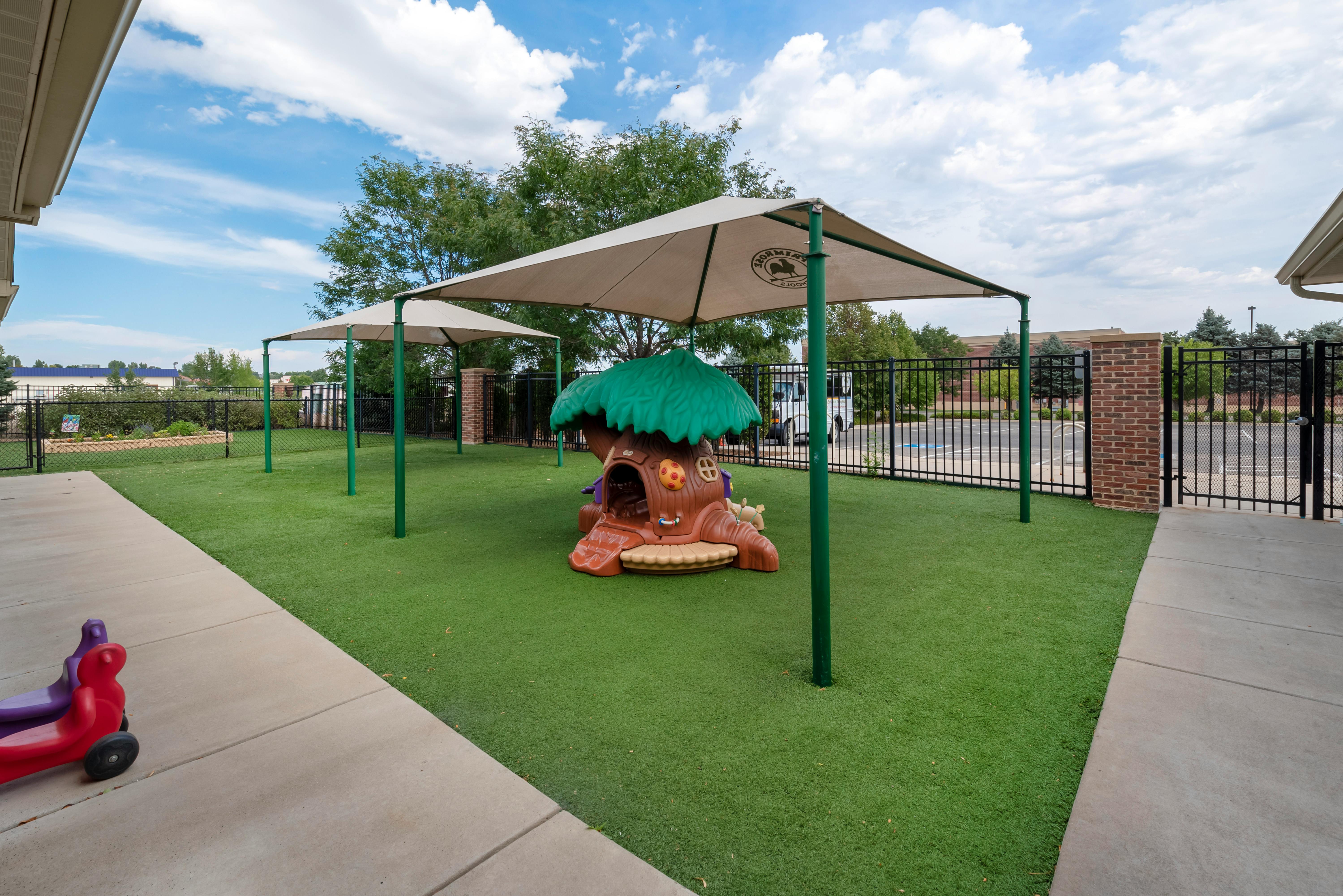 Playground with turf ground, shade canopies, and a treehouse-shaped play structure