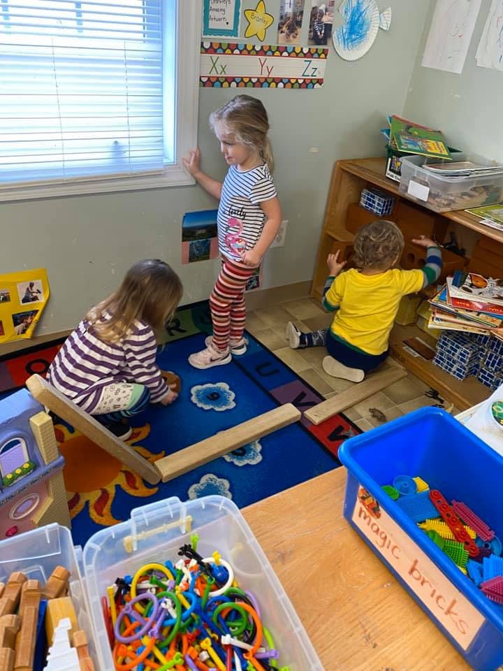 Three children playing with toys in a room
