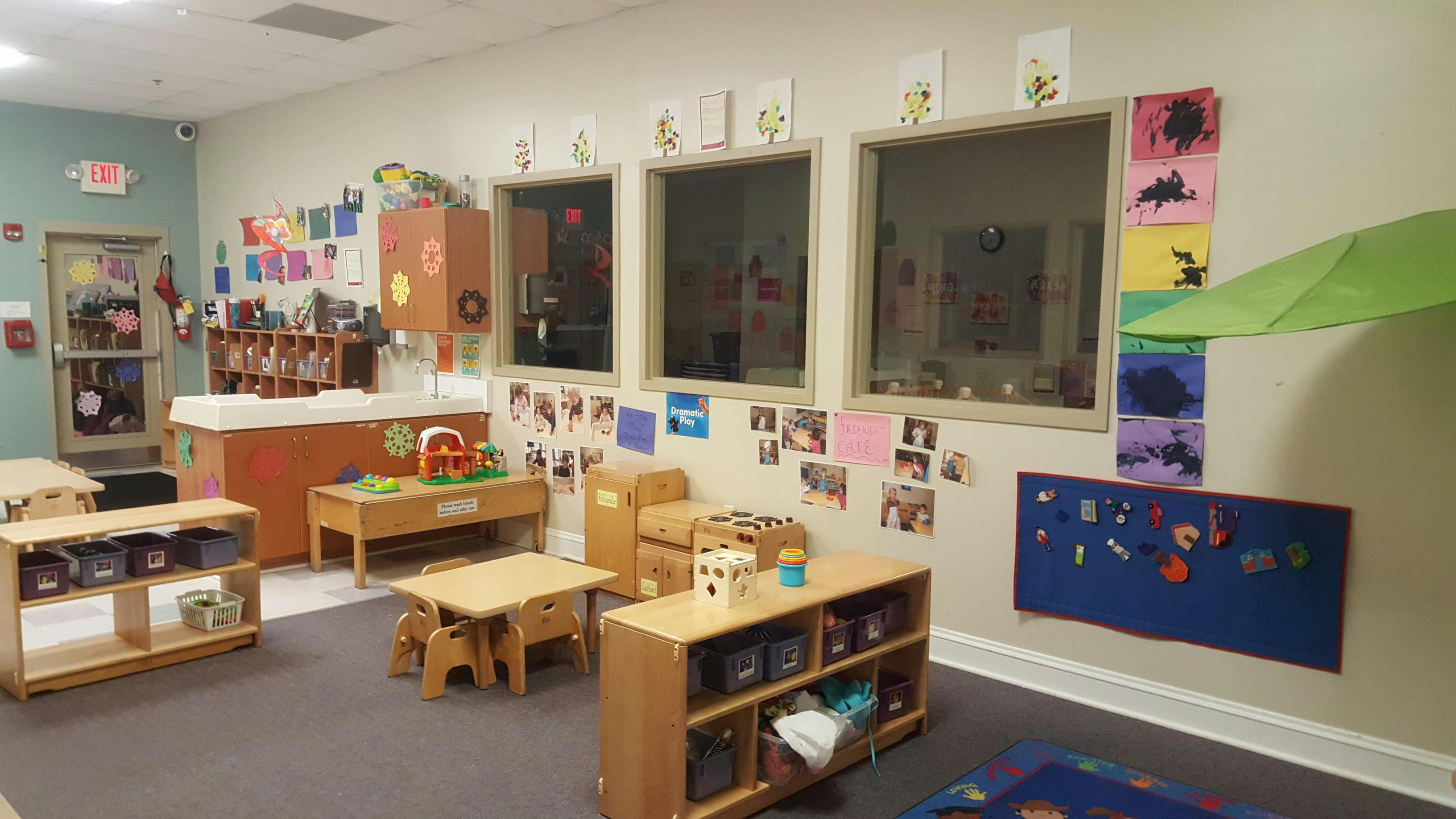 An empty early childhood classroom with windows and play areas