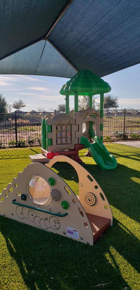 Playground with a green and tan play structure and a separate activity panel