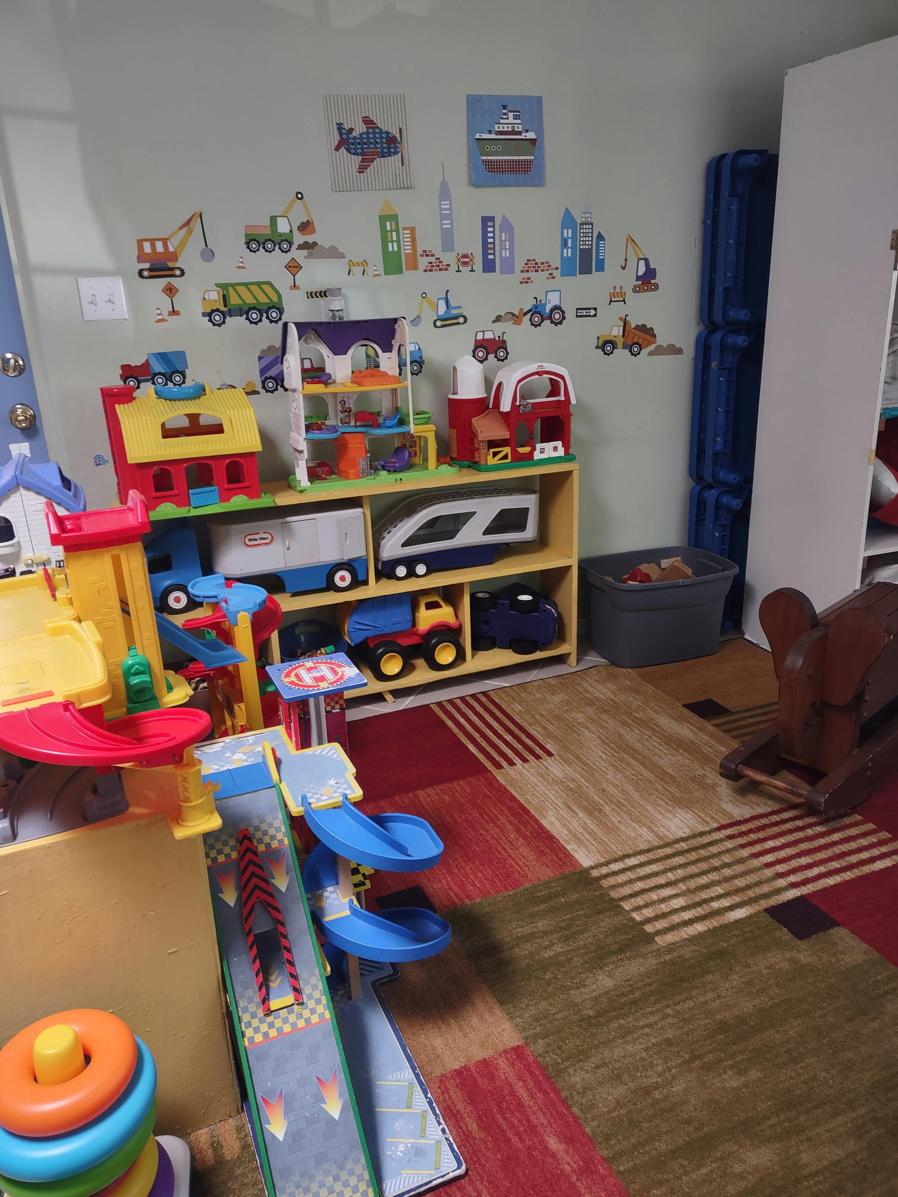 Selection of various plastic toy vehicles and structures in a playroom
