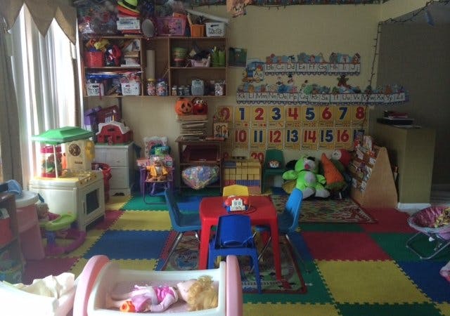 Playroom with colorful floor mats, small table and chairs, and shelves of toys