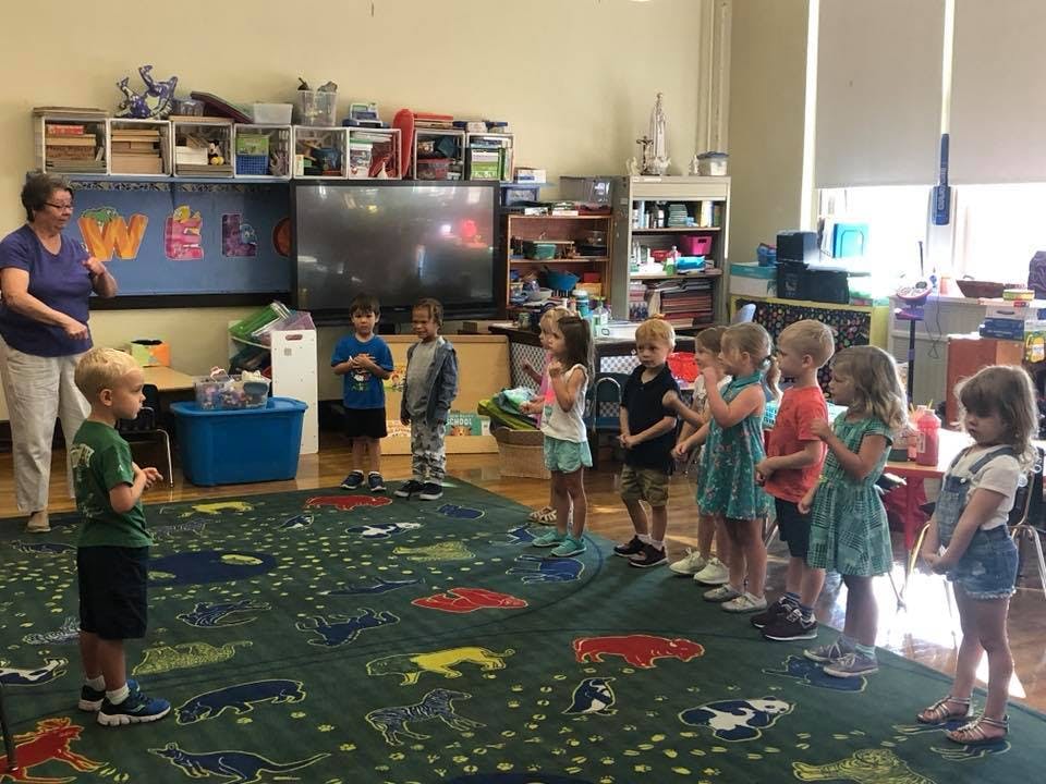 Adult and children standing in a classroom