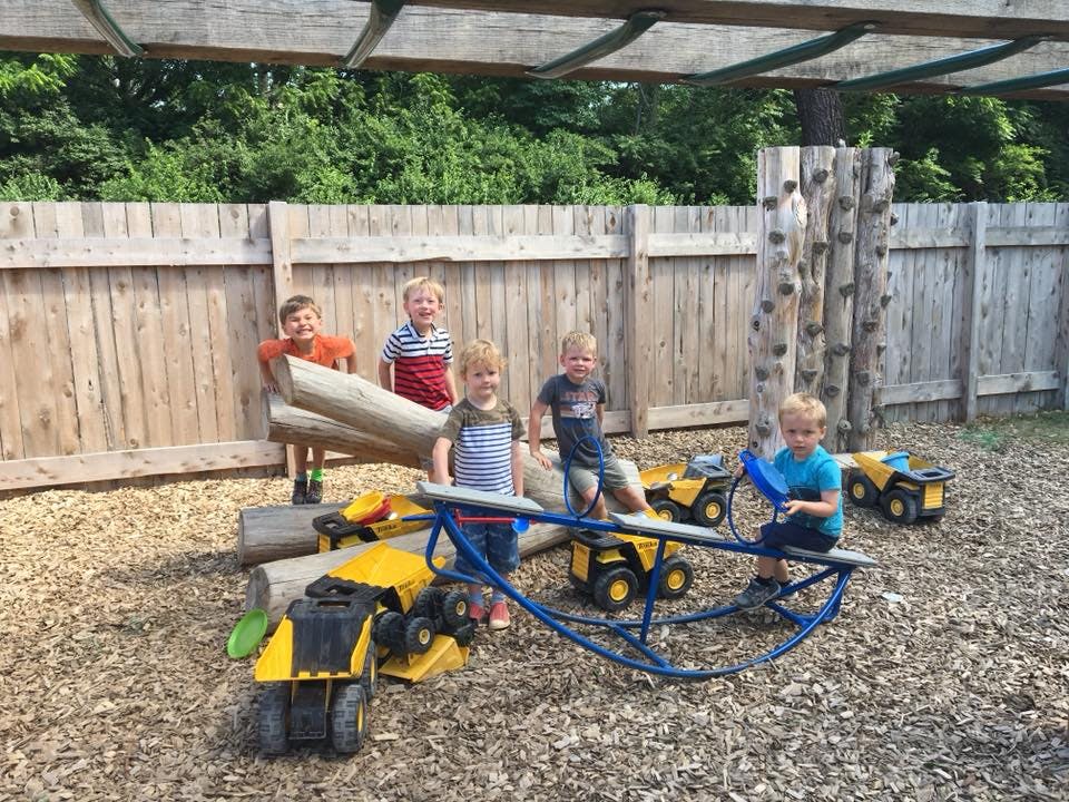 Children playing with toy trucks and a seesaw on a playground