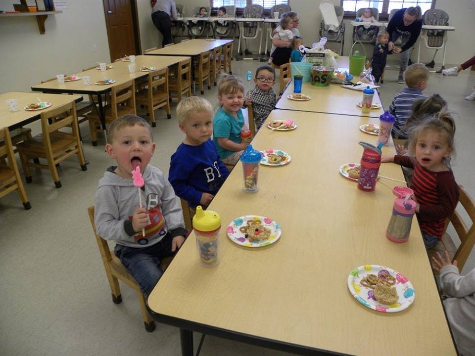 Children sitting at tables with plates and drinks