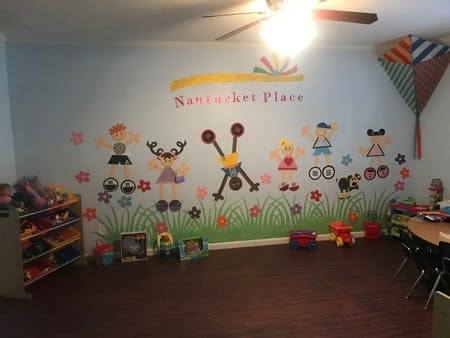 Playroom with wall mural of children figures and text "Nantucket Place"