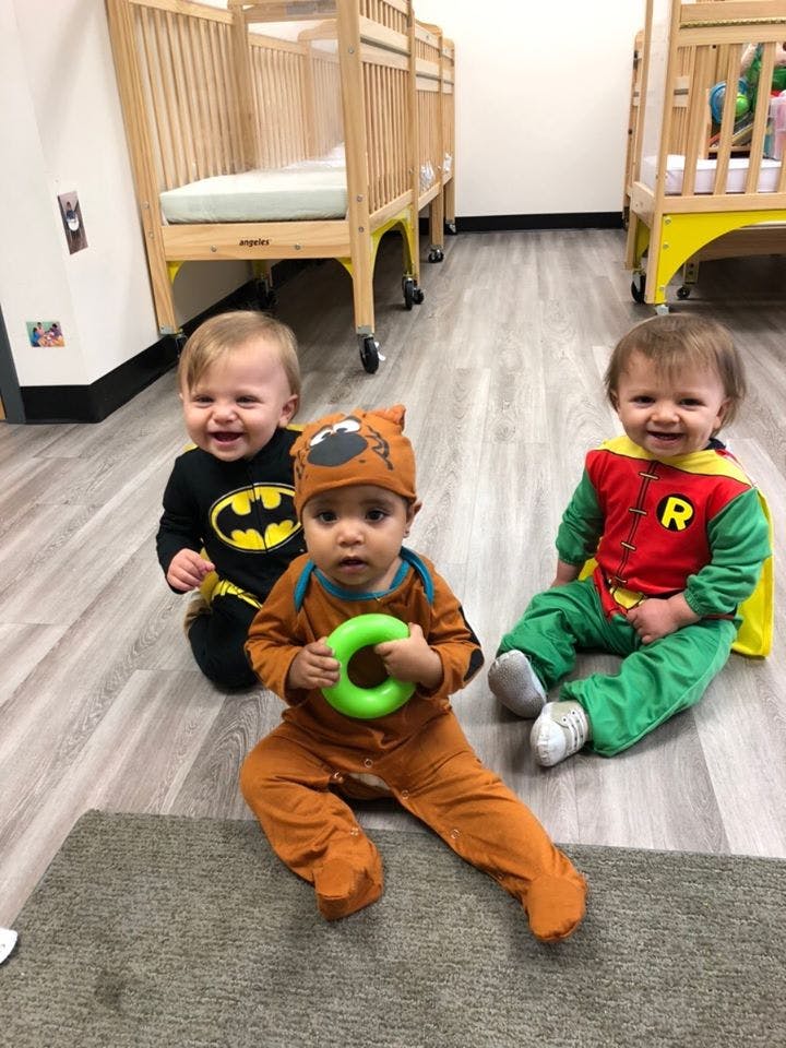 Three children in costumes sitting on the floor