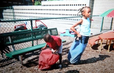 Two children playing with sacks outdoors