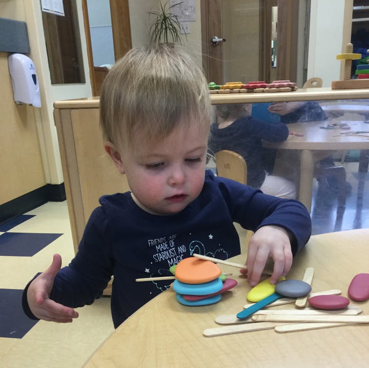 Child playing with colorful stacking toys and craft sticks
